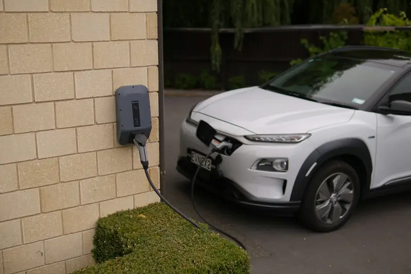 An electric car charging from a wall-mounted home charger