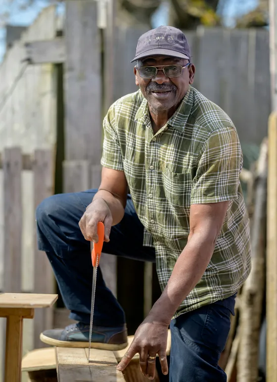 A tradesman sawing timber in a back garden